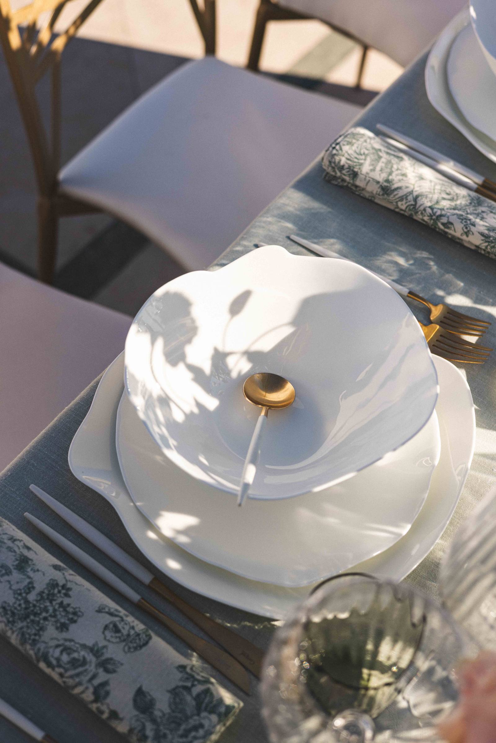 Une assiette blanche et sa cuillère dorée, vue de haut