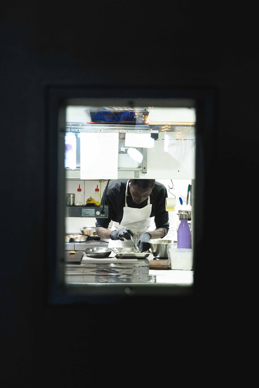 Un chef dressant une assiette, vu depuis le passe