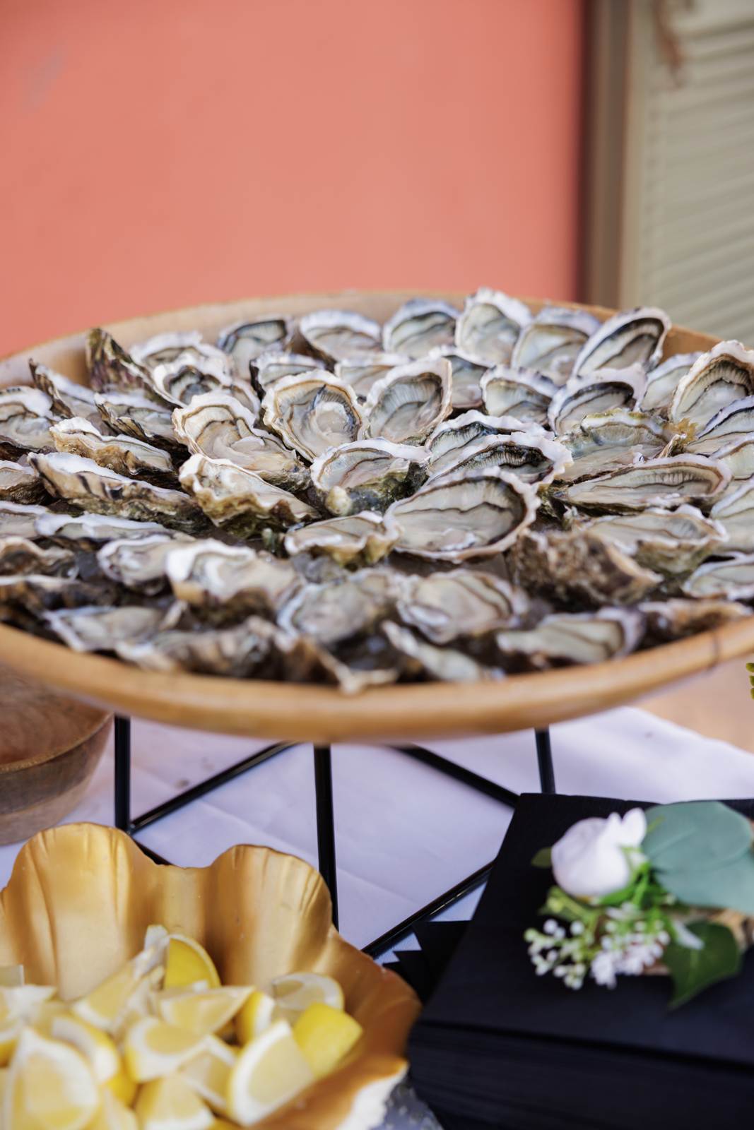 A large platter of opened oysters beside a bowl of lemons