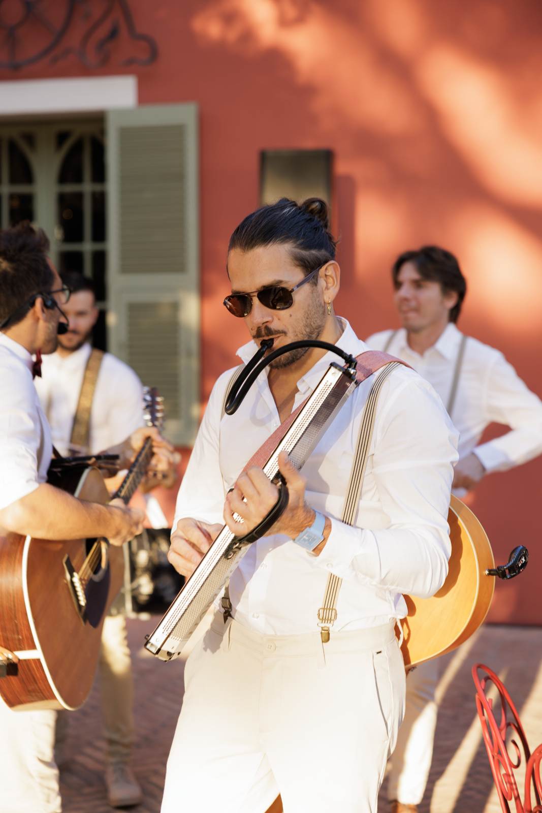 Musicians in white shirts playing in front of a red façade