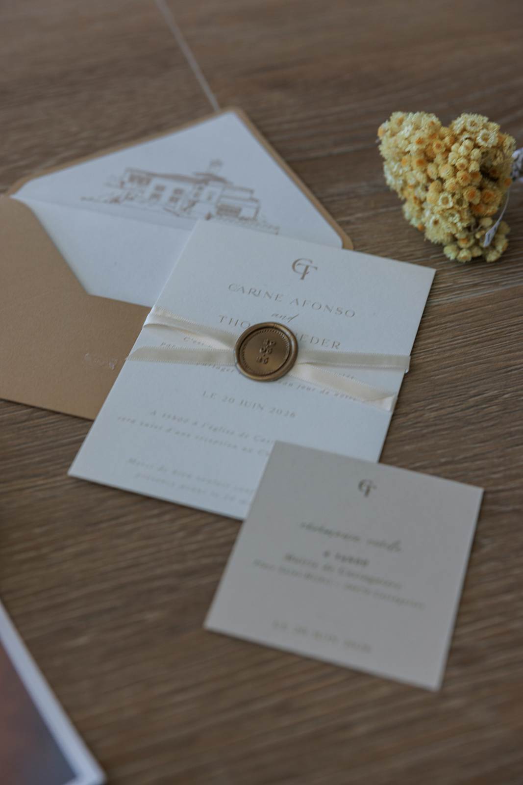 The wedding invitation, sealed with wax, beside a bunch of dried flowers