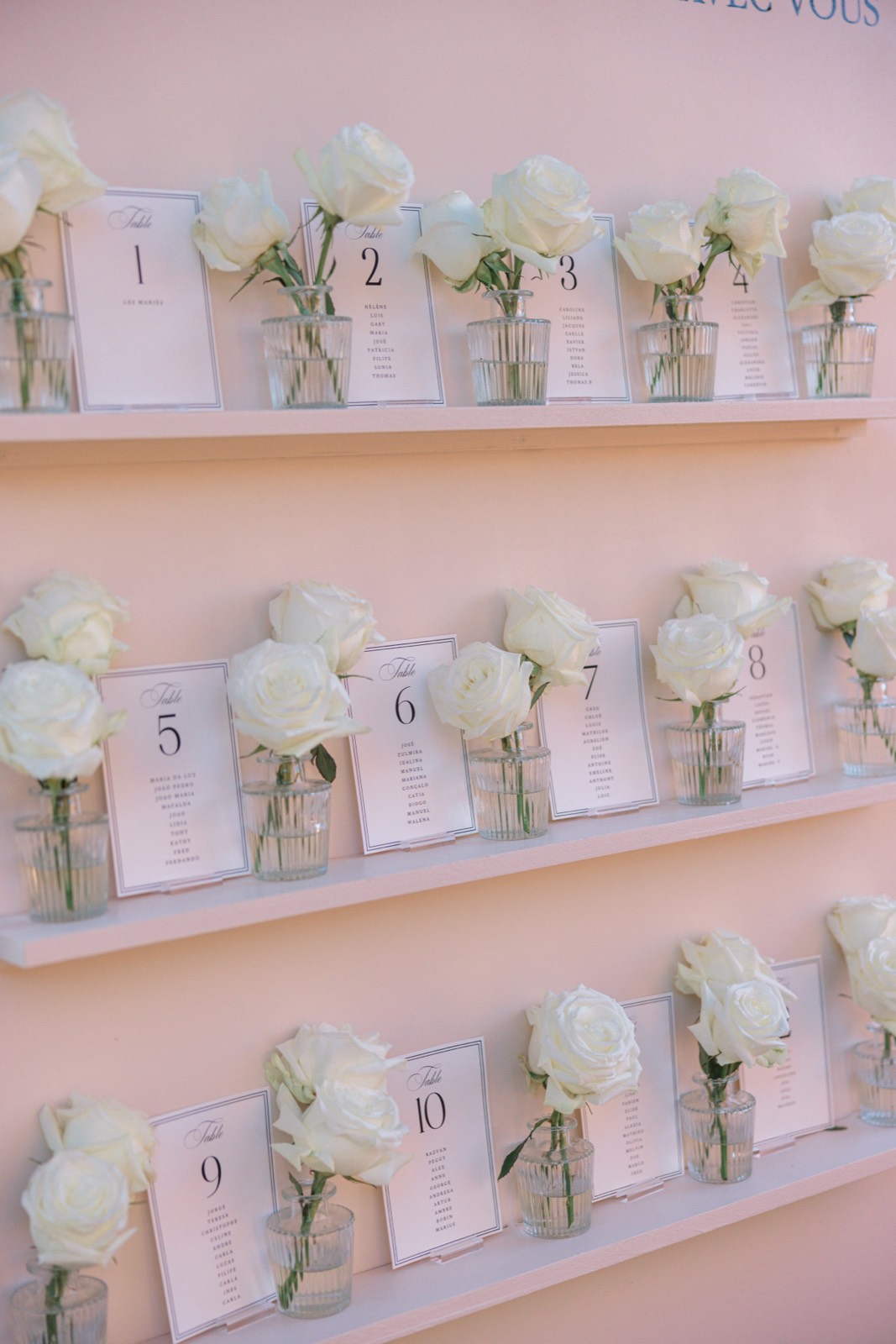 A seating plan displayed on shelves with single white roses