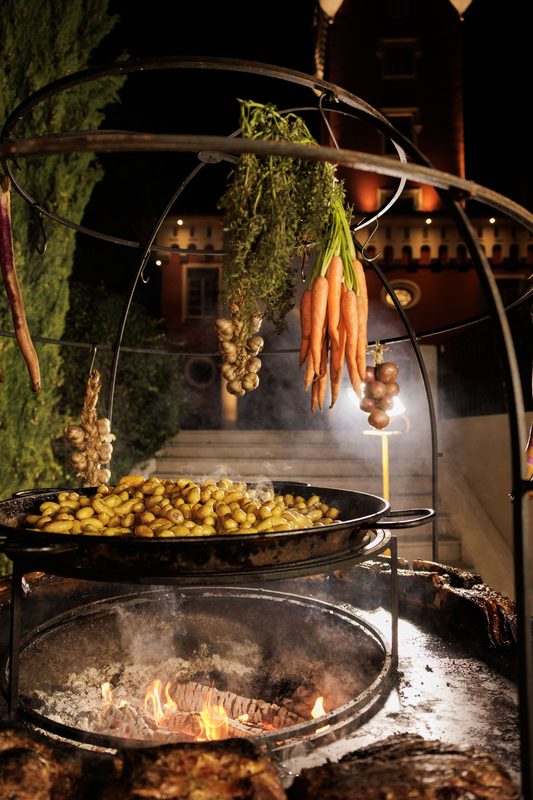 Potatoes and vegetables cooking on a brazier at night