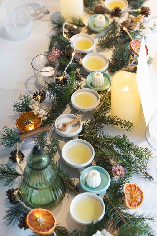 Une table d’hiver dressée de bougies, de branches de pin et de petites coupes