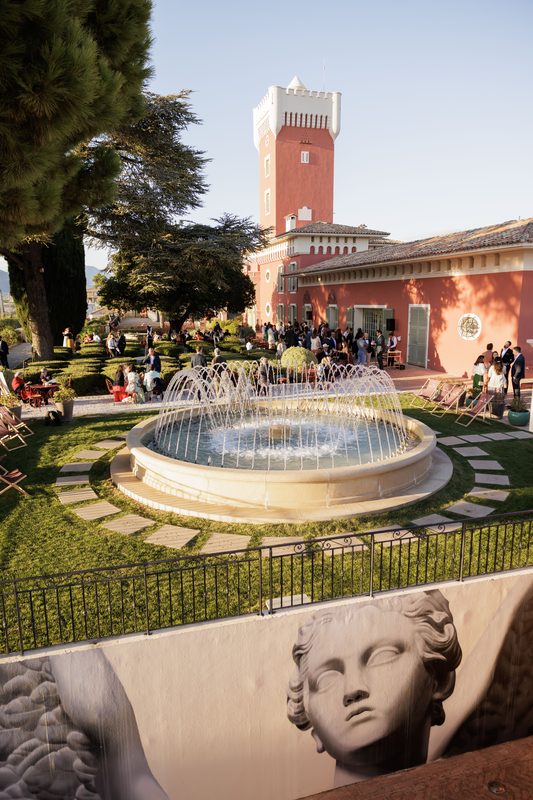 Un cocktail dans les jardins d’une villa à tour, autour d’une fontaine